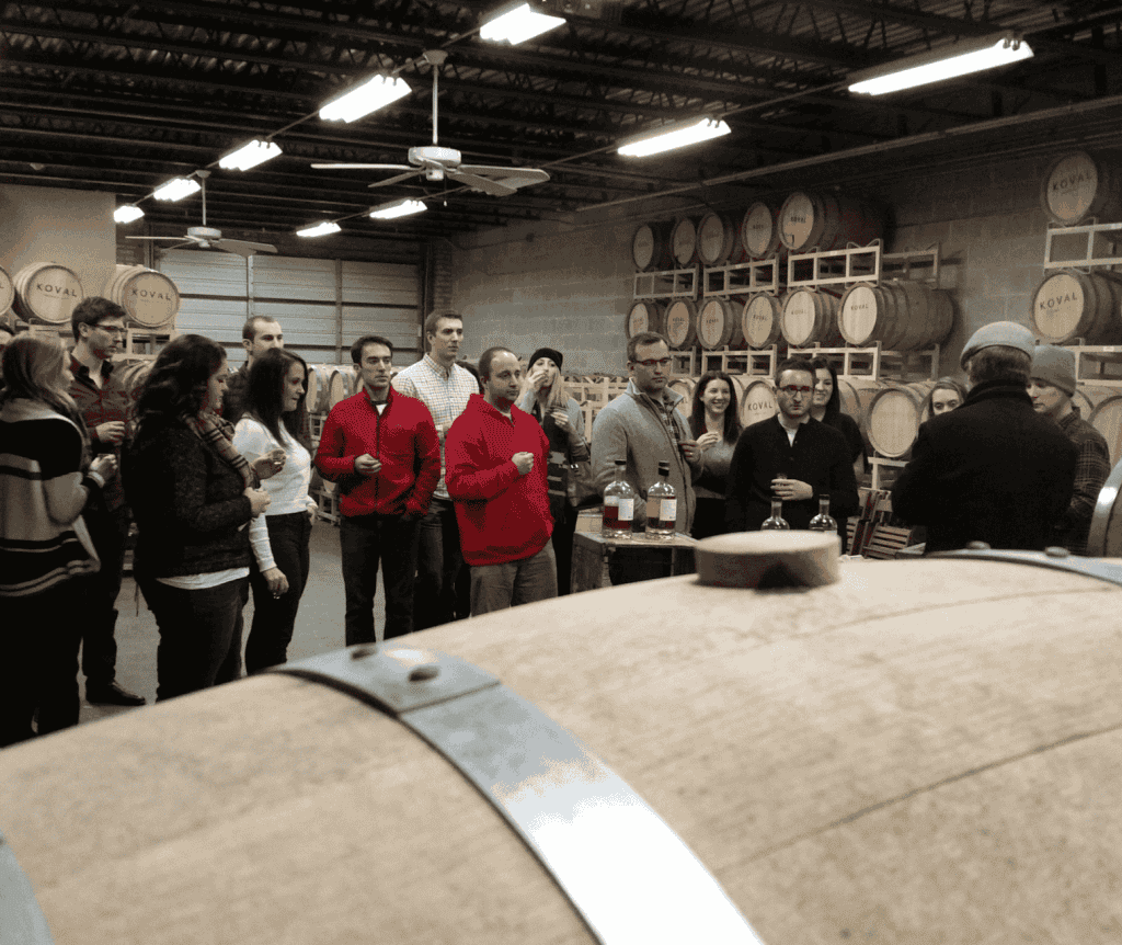 people standing next to barrels at a private distillery tour