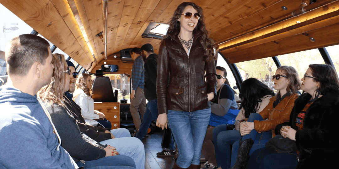 people sitting in the barrel bus with a lady standing wearing sunglasses