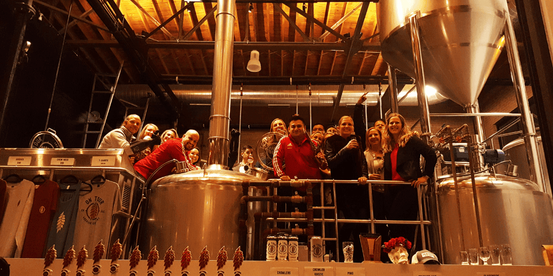 people standing next to brewing equipment on a public brewery tour