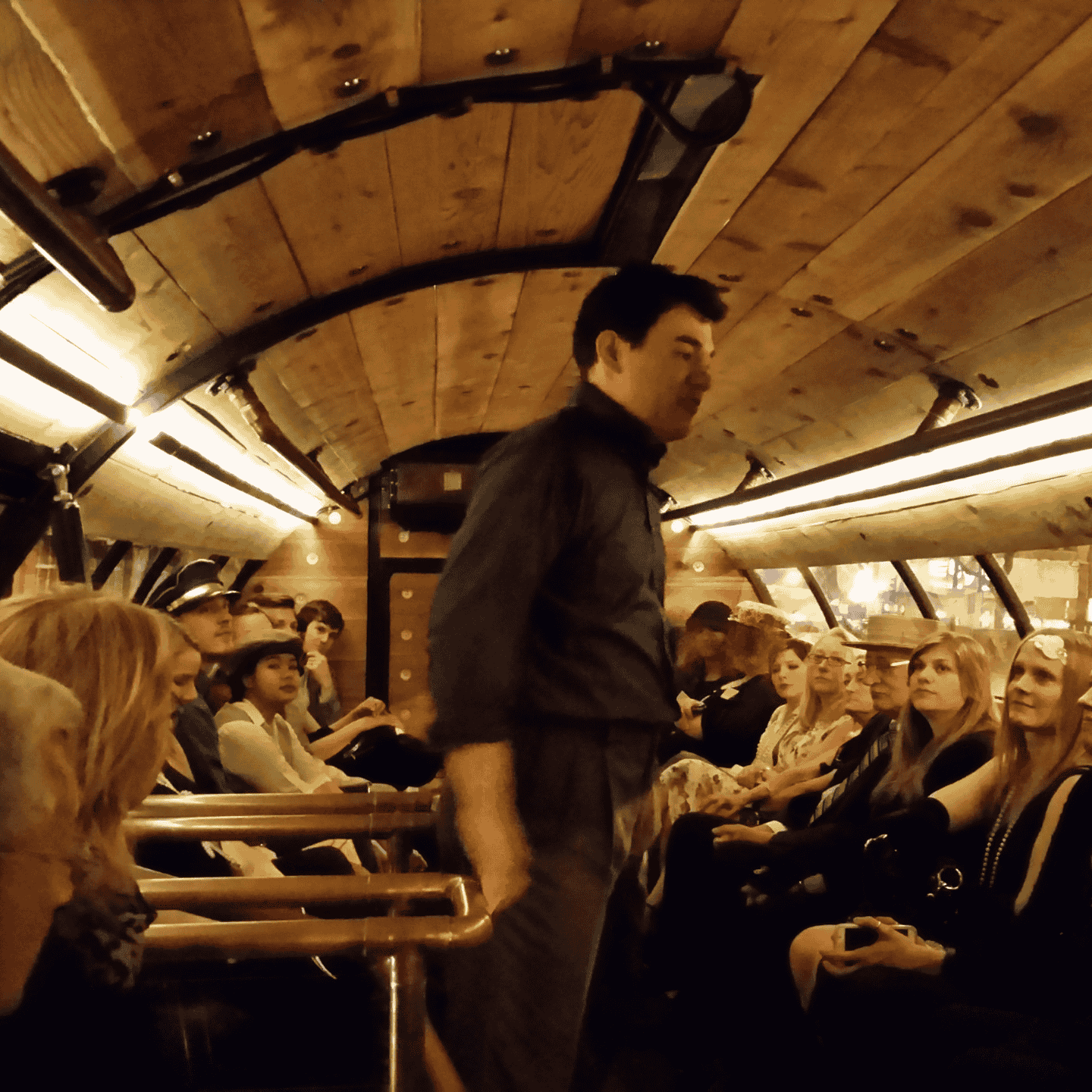 people sitting on a the barrel bus listening to a brewery tour guide speak