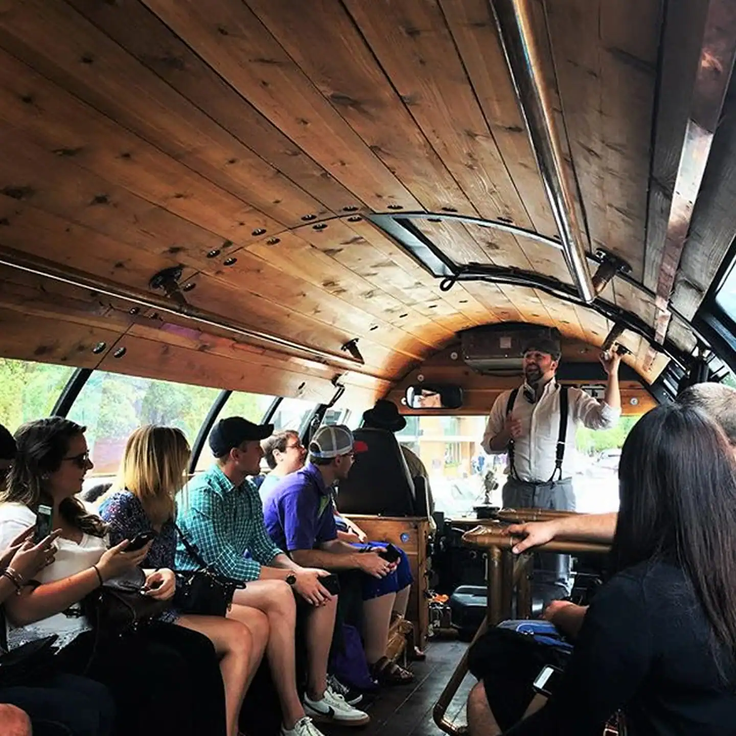 people sitting on the barrel bus listening to the brewery tour guide speak