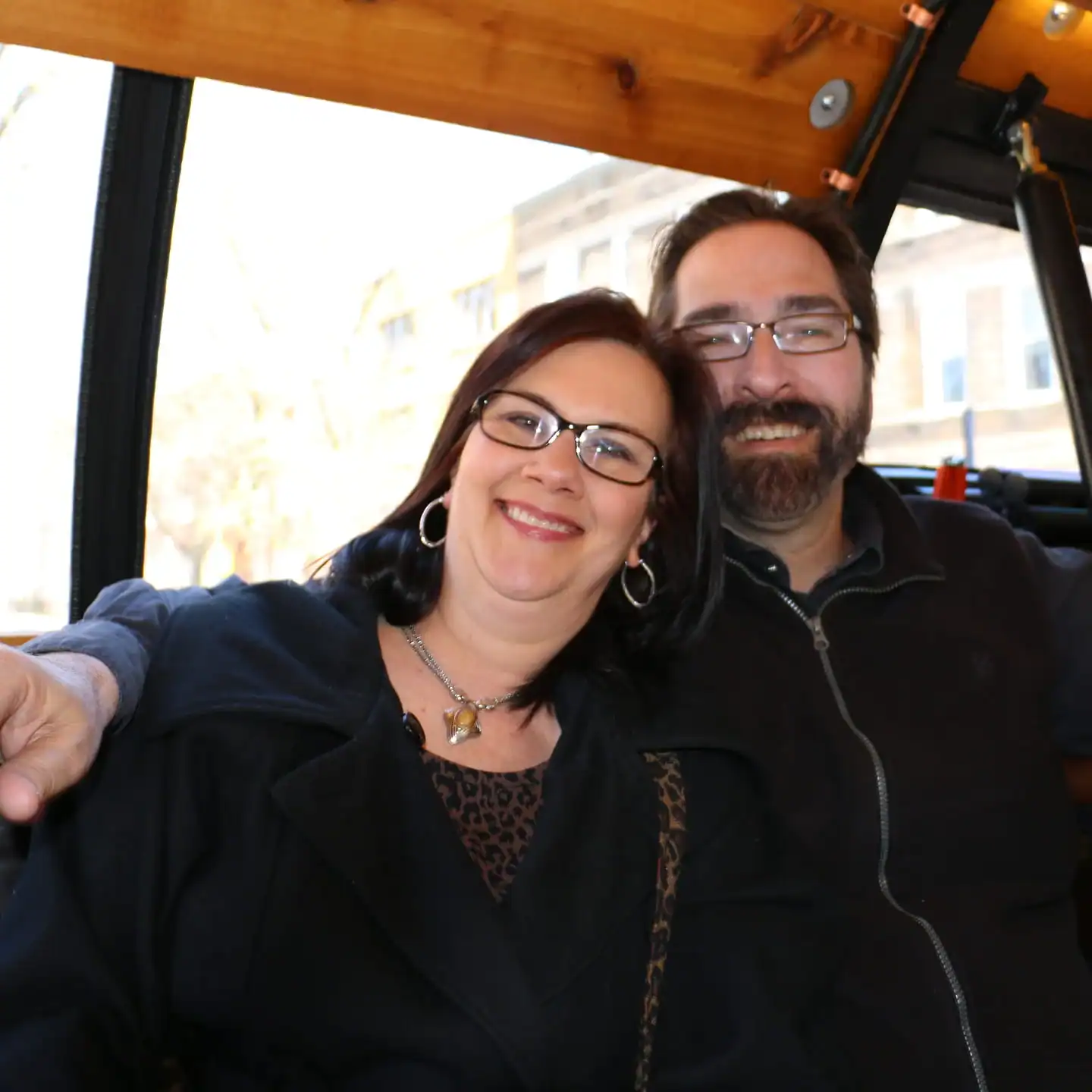 two people posing while sitting in the barrel bus