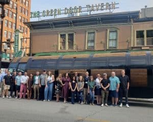 group of people standing in front of the barrel bus outside the green door tavern