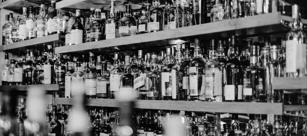 black and white photo of wall of a variety of whiskeys